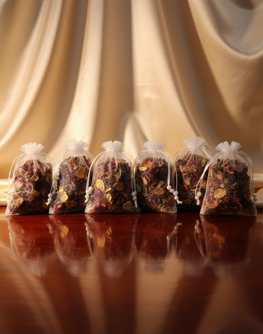 Small bags of dried herbs or spices on a reflective surface with draped fabric in the background