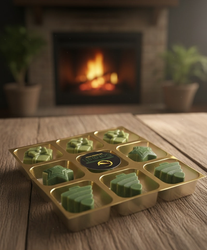 Gold mold with green leaf-shaped objects on a wooden surface with a fireplace in the background