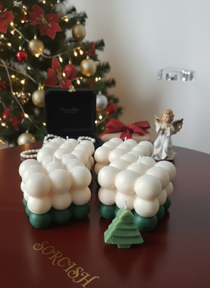 Decorative letter 'K' made of white balloons with green bases in front of a Christmas tree.