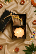 Gift set with a candle, pouch, and bottle on a satin surface with decorative elements.