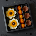 Decorative cookies shaped like sunflowers and pumpkins in a black box on a dark background