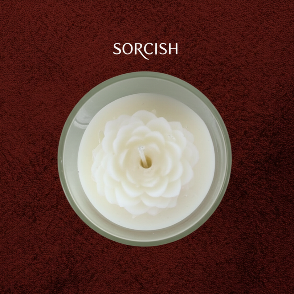 White flower-shaped candle in a glass container on a dark red background.