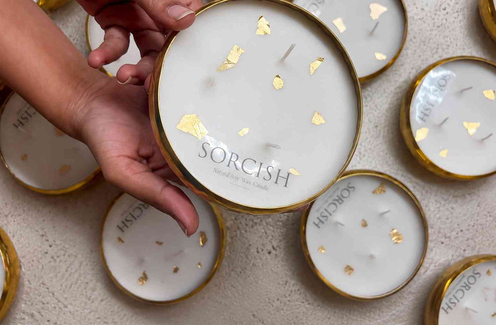 Hand holding a Sorcish candle among other similar candles on a textured surface