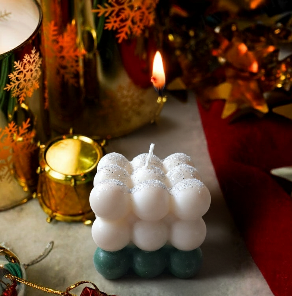 Decorative bubble candle with a lit candle in the background, surrounded by festive decorations.
