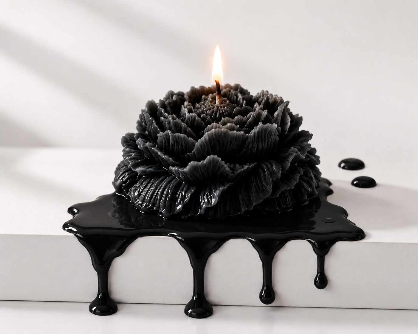 Black candle with a flame on a white surface