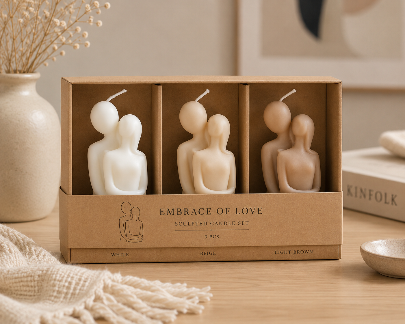 Set of three sculpted candles in a cardboard box labeled 'Embrace of Love' on a wooden surface.