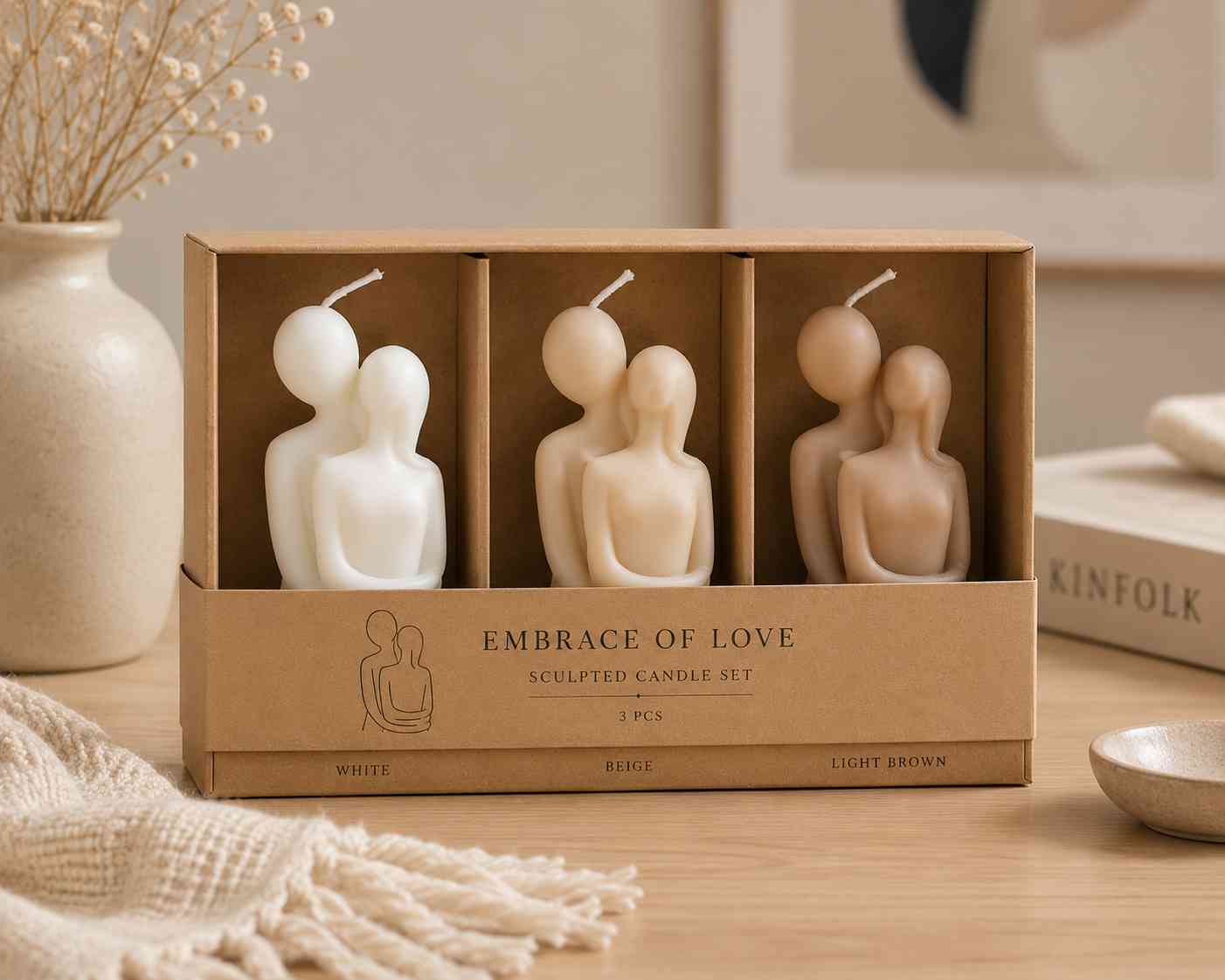 Set of three sculpted candles in a cardboard box labeled 'Embrace of Love' on a wooden surface.