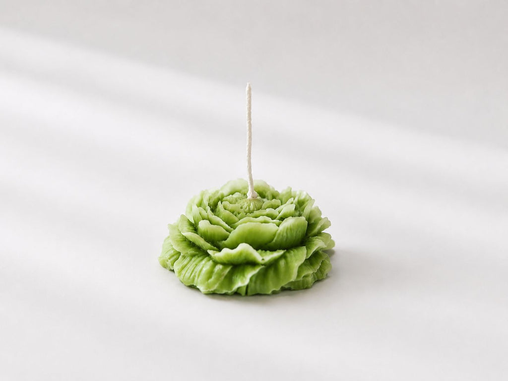 Green candle shaped like a flower on a white background