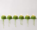 Row of green candles on a white surface with a light gray background