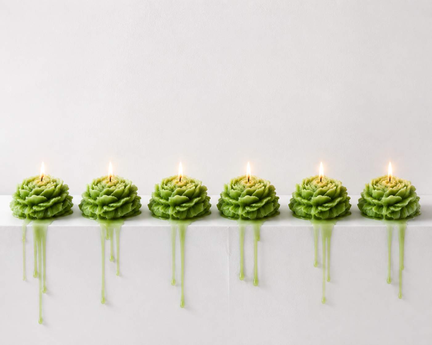Row of green candles on a white surface with a light gray background