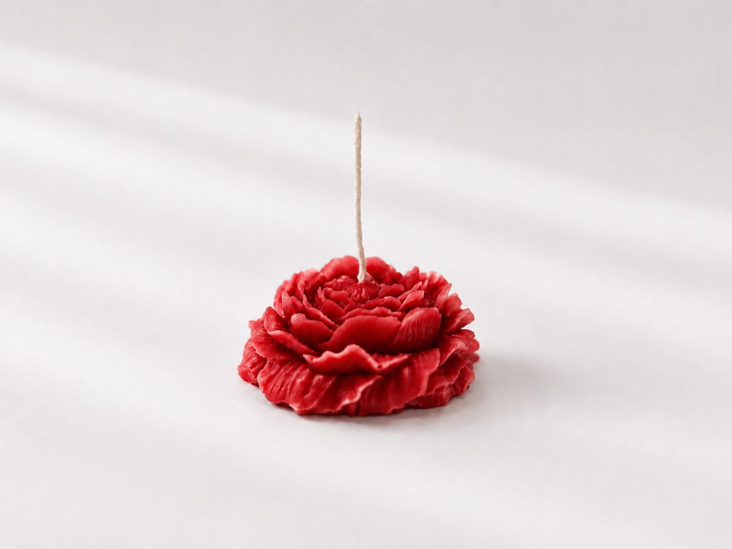 Red flower-shaped candle on a white background
