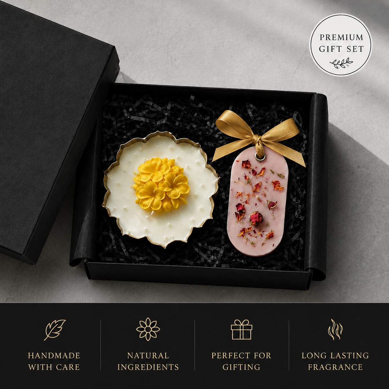 A premium gift set in an open black box on a light gray surface, featuring a white flower-shaped decorative dish with a yellow flower center and a pink oval ornament tied with a gold ribbon containing dried botanical pieces. Text badges read 'PREMIUM GIFT SET' and 'HANDMADE WITH CARE' with additional feature callouts below.